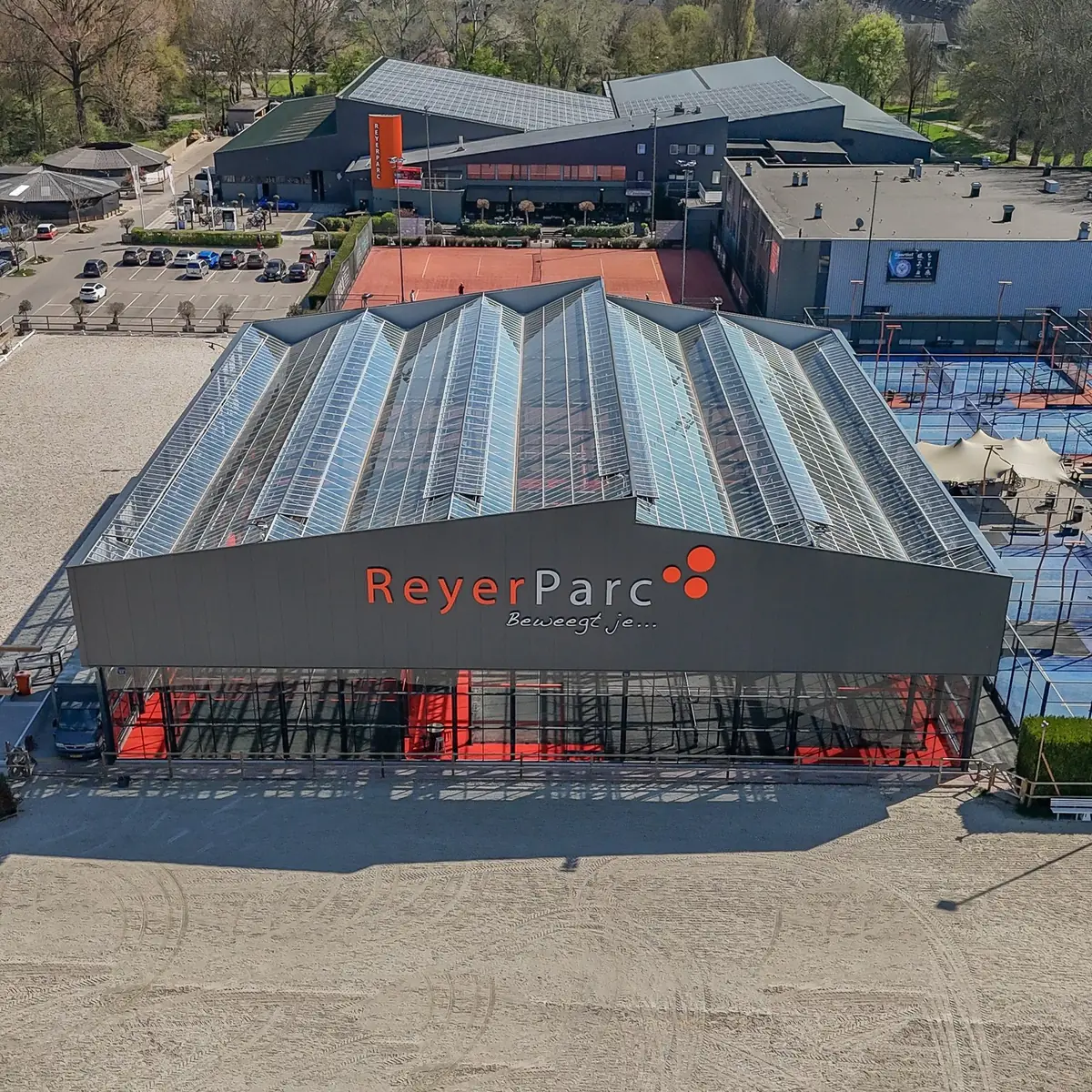 De hal op Reyerparc overdag van bovenaf: het glazen dak en de voorgevel, met de buitenbanen ernaast